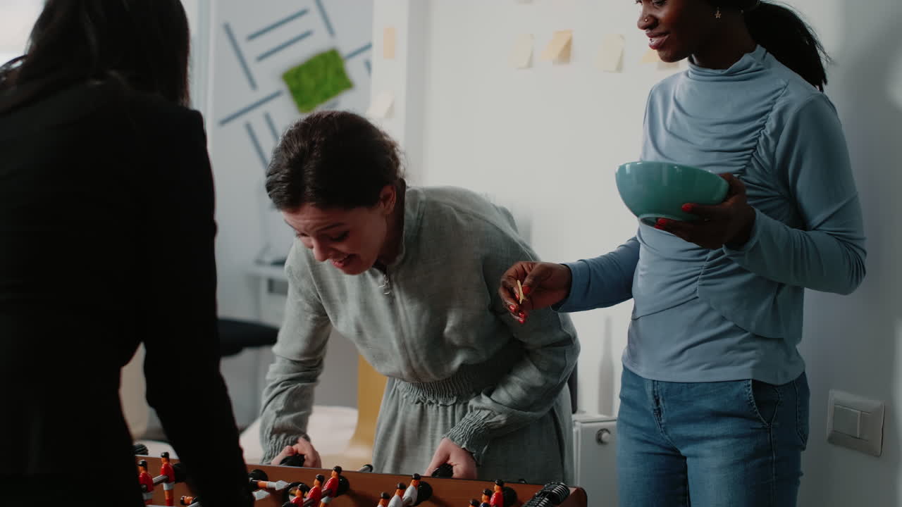 Multi ethnic colleagues playing with foosball game table