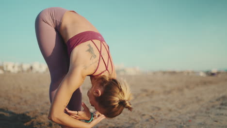 caucasian tattooed girl stretching by the sea.