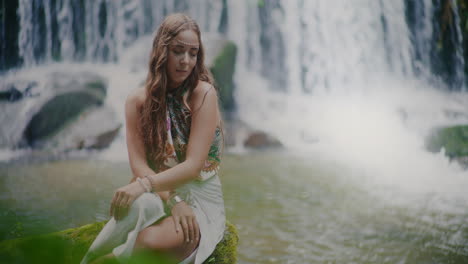 beautiful thoughtful woman in front of a waterfall