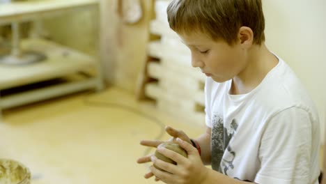 a boy works with clay in the ceramics studio