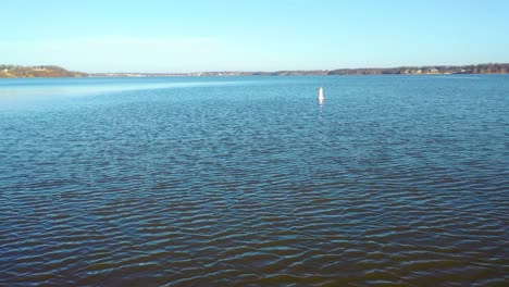 low aerial flying over lake water towards buoy floating