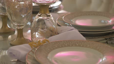 wedding reception table with porcelain plates, silverware, and etched glasses