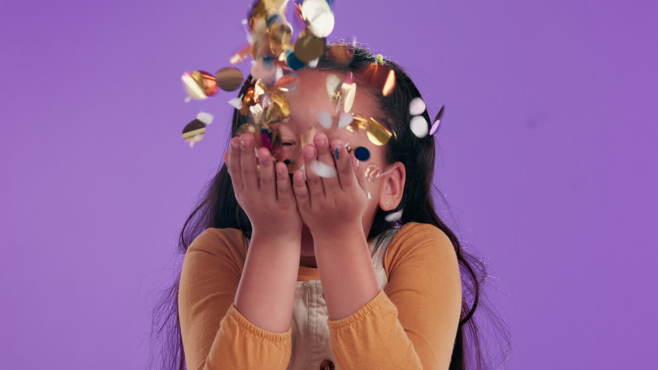 Girl blowing confetti on purple background