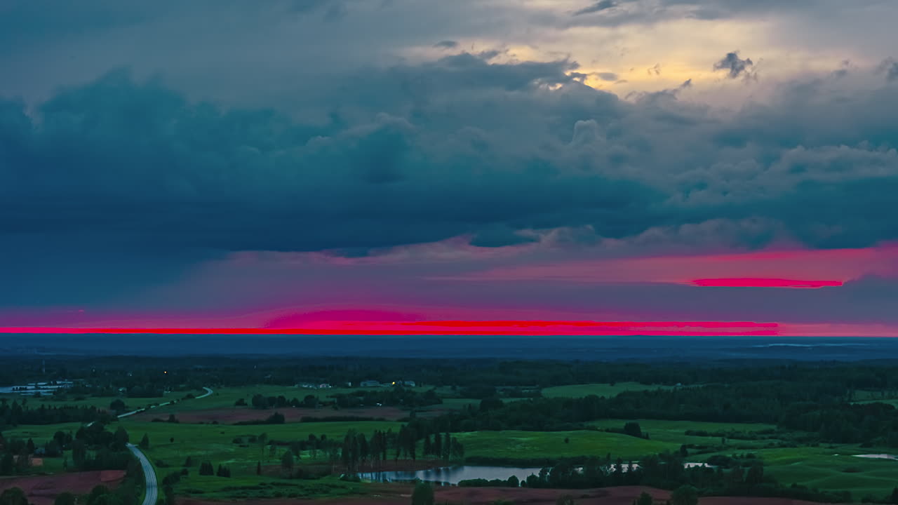 Beautiful timelapse of red pink sunset sky bursting and dissapearing on dark countryside horizon