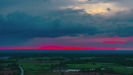 beautiful timelapse of red pink sunset sky bursting and dissapearing on dark countryside horizon