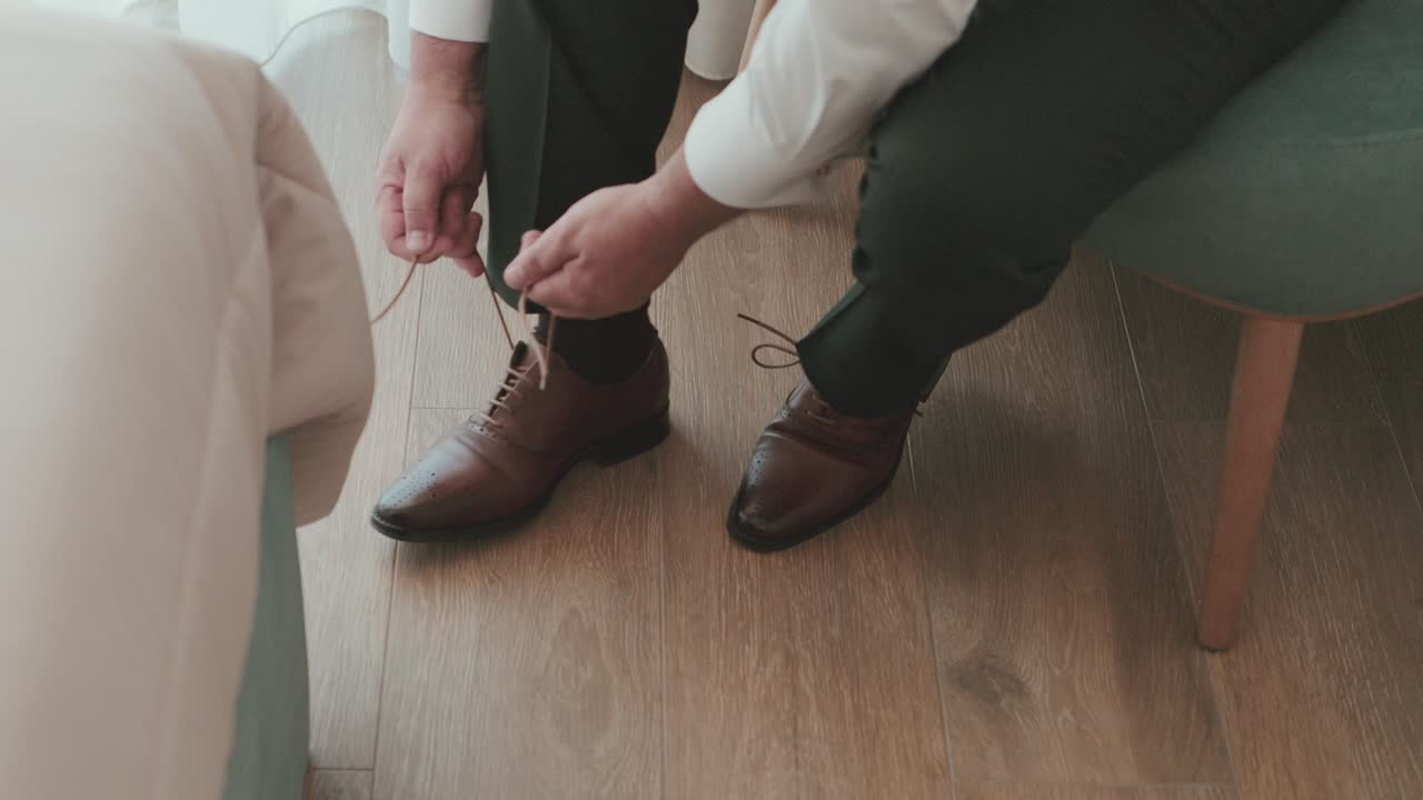 Pria mengikat sepatu kulit cokelat saat persiapan pernikahan di dalam ruangan