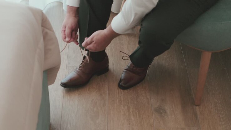 Man tying brown leather shoes during wedding preparation indoors
