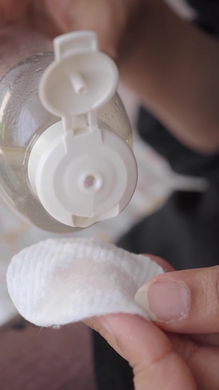 Pouring Micellar Water onto a Cotton Pad for Skincare