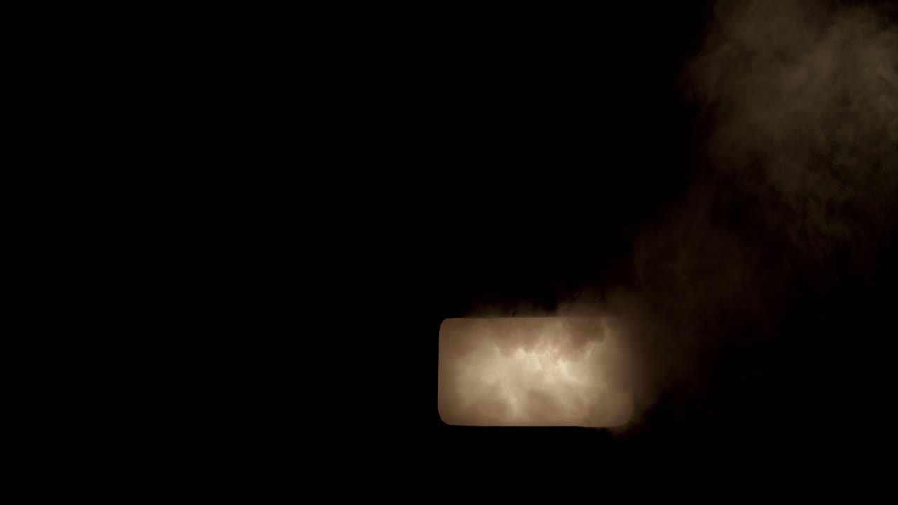 Slow motion glowing smoke billows out of a window and to the top of frame.