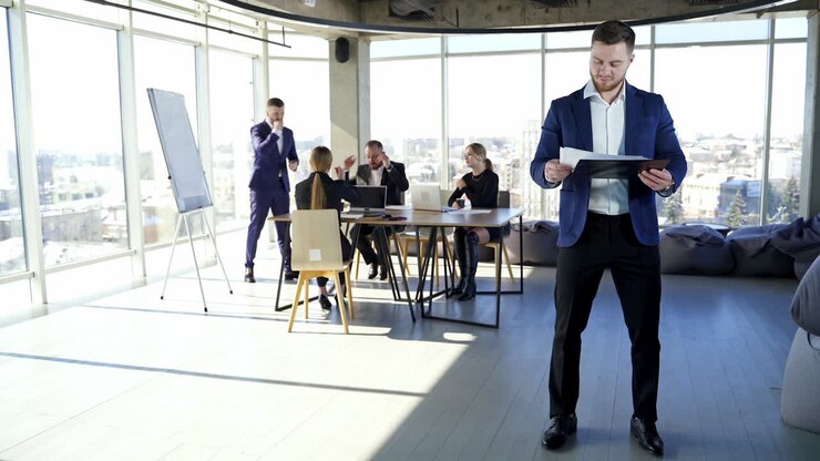 Uomo d'affari affascinante che pensa a un nuovo progetto. Riunione d'affari di gruppo in un ufficio elegante