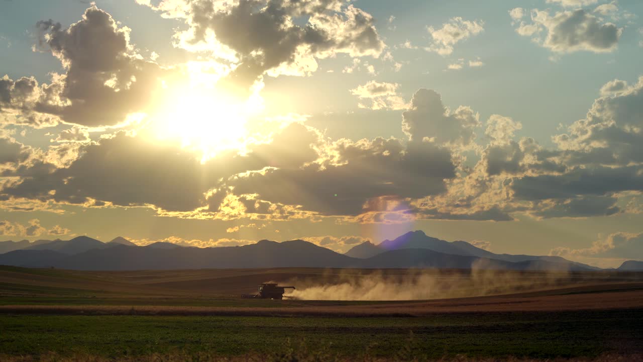 cosechadora en la zona rural de colorado, en un contexto de montañas y puesta de sol