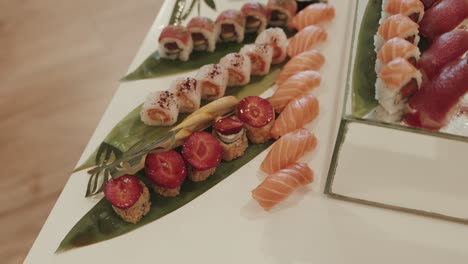 sushi assortment with salmon nigiri and strawberry rolls on tropical leaves at sushi station