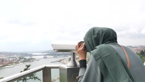 woman in hijab looking through telescope at istanbul city view