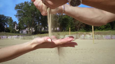 sand pouring from male hand to woman hand. hands sand. hand pour sand