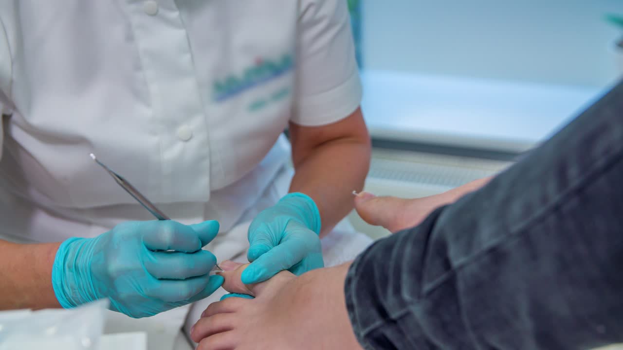 A stationary shot of a pedicurist doing treatment on feet