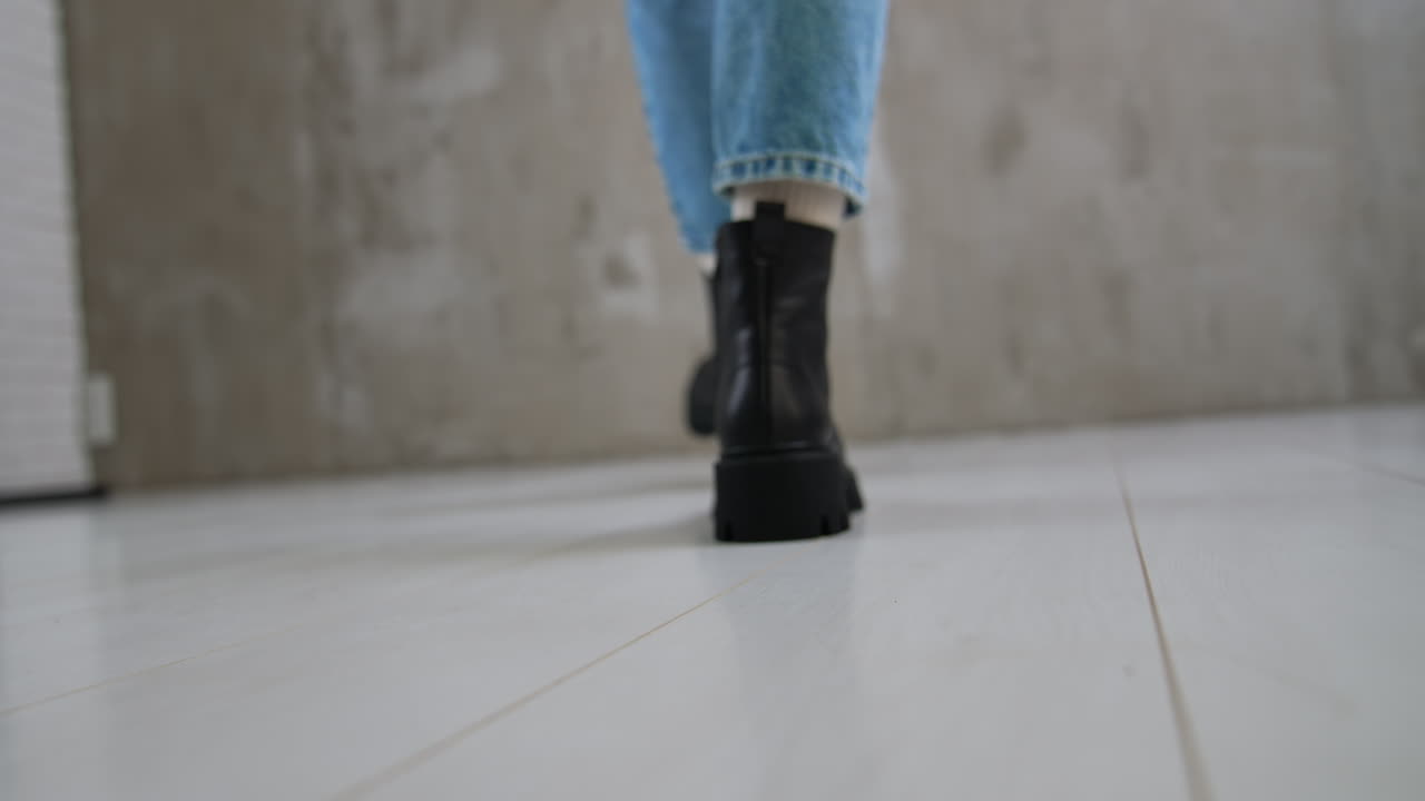 Woman walking in black boots and blue jeans