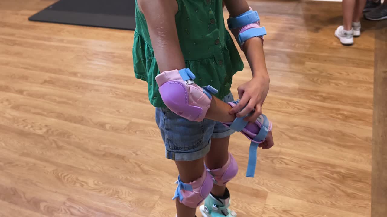 Child putting on knee and elbow pads for roller skating