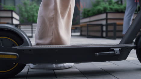 piernas de mujer montando patineta en zapatillas blancas yendo lejos en el centro de la ciudad de cerca.
