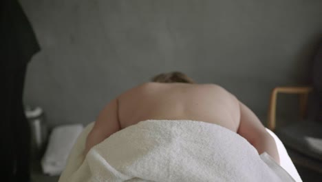 chubby woman lying on massage table while therapist is getting ready