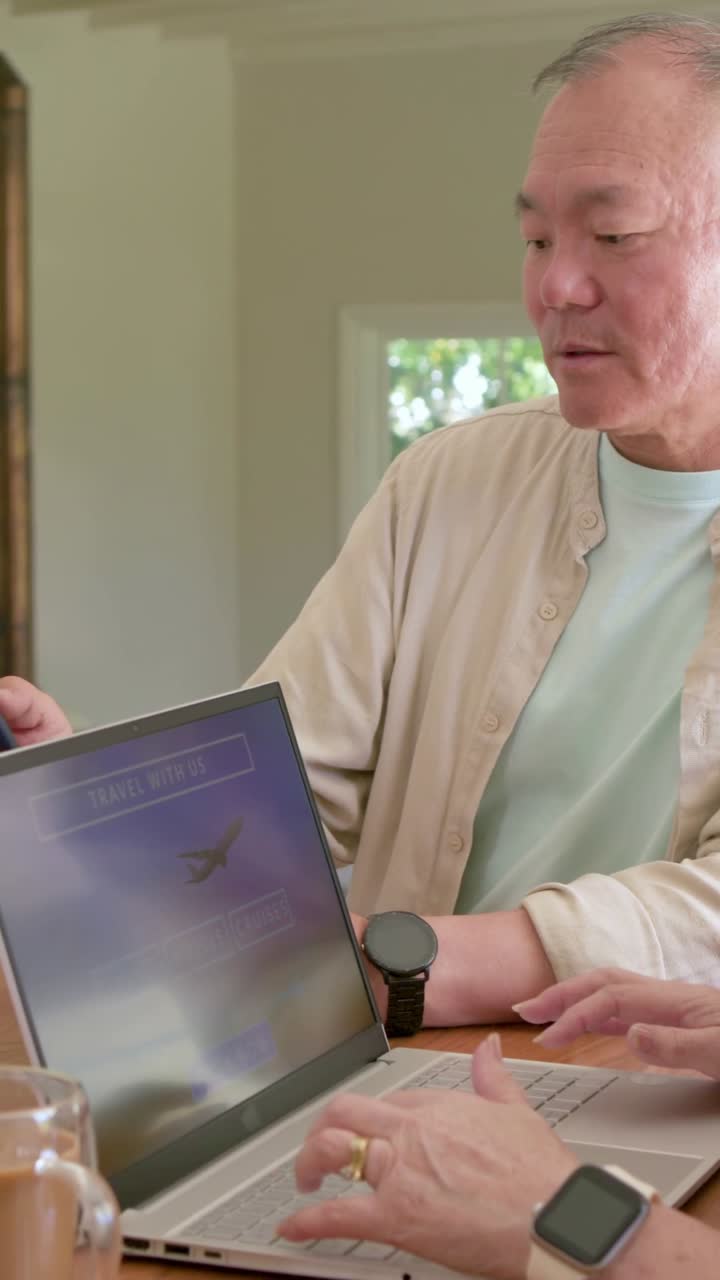 Vertical video: Moving laptop, man guiding wife typing at home table booking flight with passport