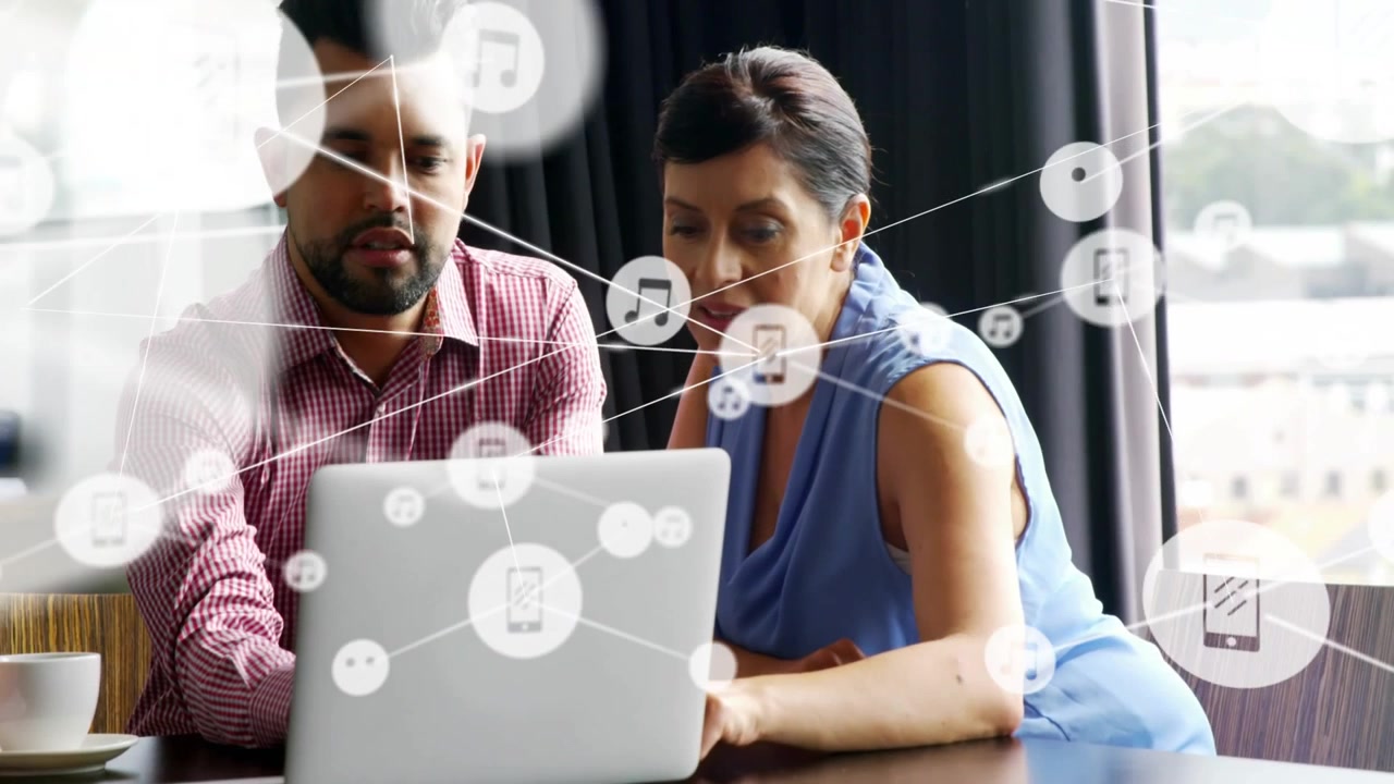 Two coworkers pointing, reviewing laptop at table while node overlay appearing causing joint focus