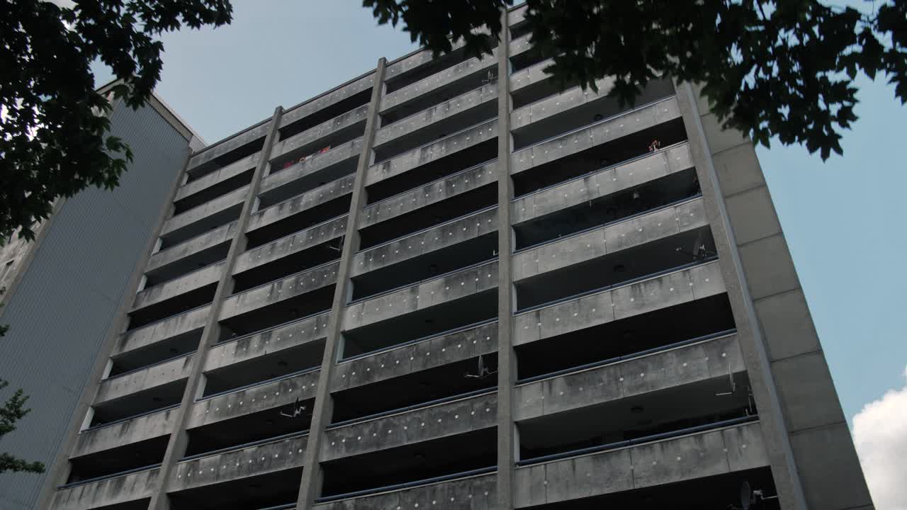 Slow motion reveal of an aged residential high-rise in a low-income area with satellite dishes