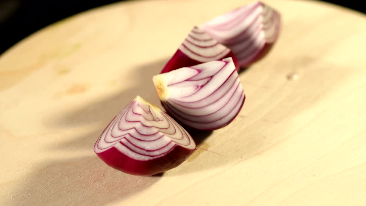 A girl is cutting a red onion on a cutting board.