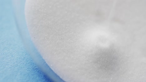 Video-of-close-up-of-hourglass-with-white-sand-pouring-with-copy-space-on-blue-background