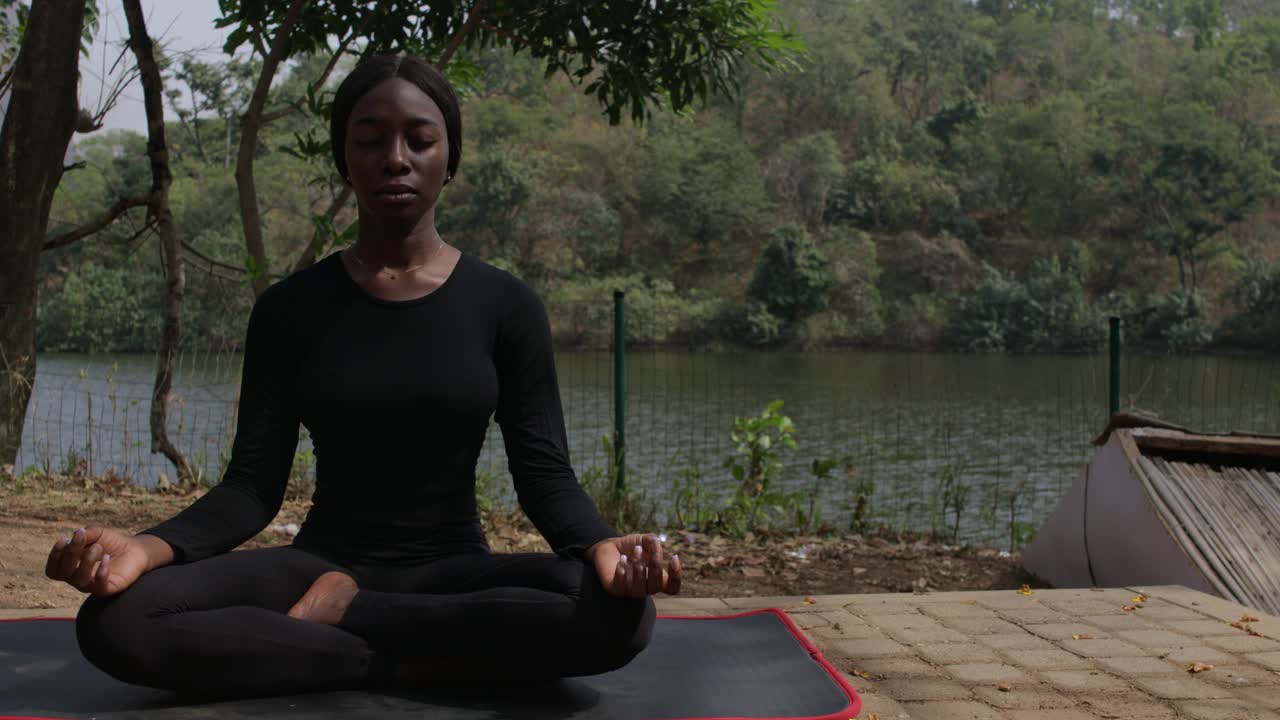 una dama durante el yoga, meditando en la pose fácil junto al lago