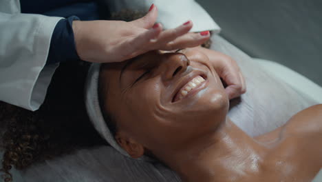 smiling woman enjoying massage after beauty procedure closeup. hands rub cream