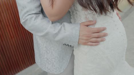 新郎が新婦を抱きしめるクローズアップ写真結婚式の服装の複雑な詳細を示しています