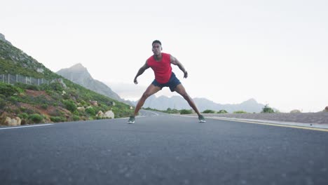 african american man performing stretching exercise and running on the road