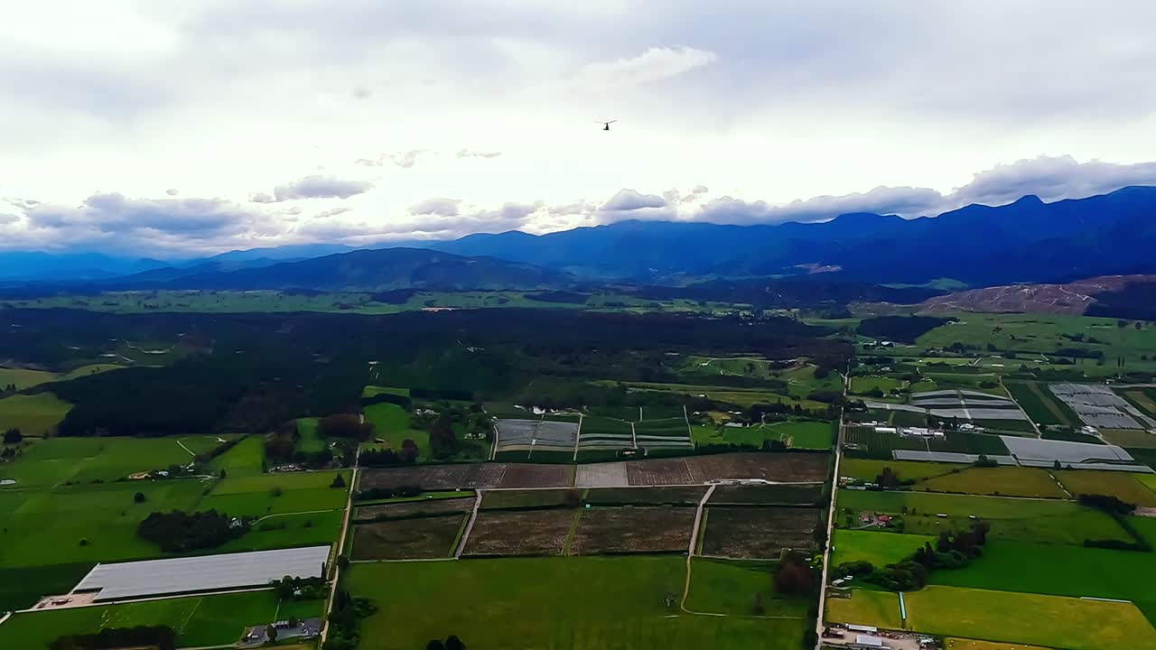 POV helicopter aerial flying over the rolling green hills and forests of the Motueka valley, New Zealand