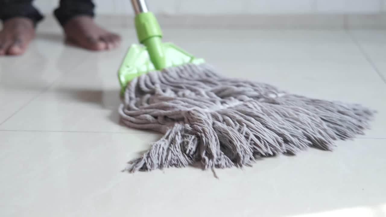 persona limpiando un piso de azulejos