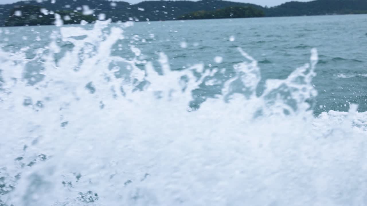 Dynamic ocean waves crash against a boat, capturing the serene beauty of Railay Beach, Krabi, Thailand