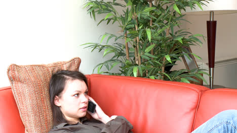 Relaxed-woman-talking-on-phone-sitting-on-sofa