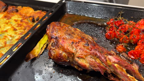 Delicious-roasted-leg-of-lamb-with-cherry-tomatoes-and-potatoes,-soft-tender-meat-cooked-in-the-oven,-4K-shot