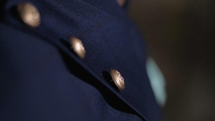 A close-up shot of blue fabric with gold buttons, showing elegance and detail in Slow Motion