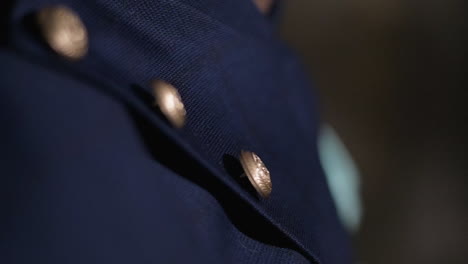 a close-up shot of blue fabric with gold buttons, showing elegance and detail in slow motion