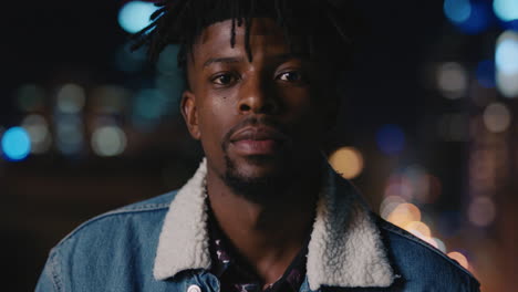 retrato atractivo hombre afroamericano en el techo por la noche sonriendo feliz disfrutando de la vida nocturna urbana con luces de la ciudad bokeh en el fondo