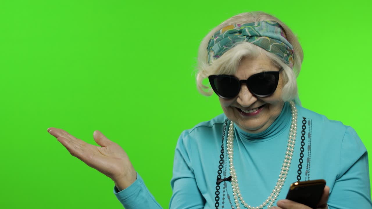 Nonna caucasica che usa lo smartphone, indicando qualcosa con la mano