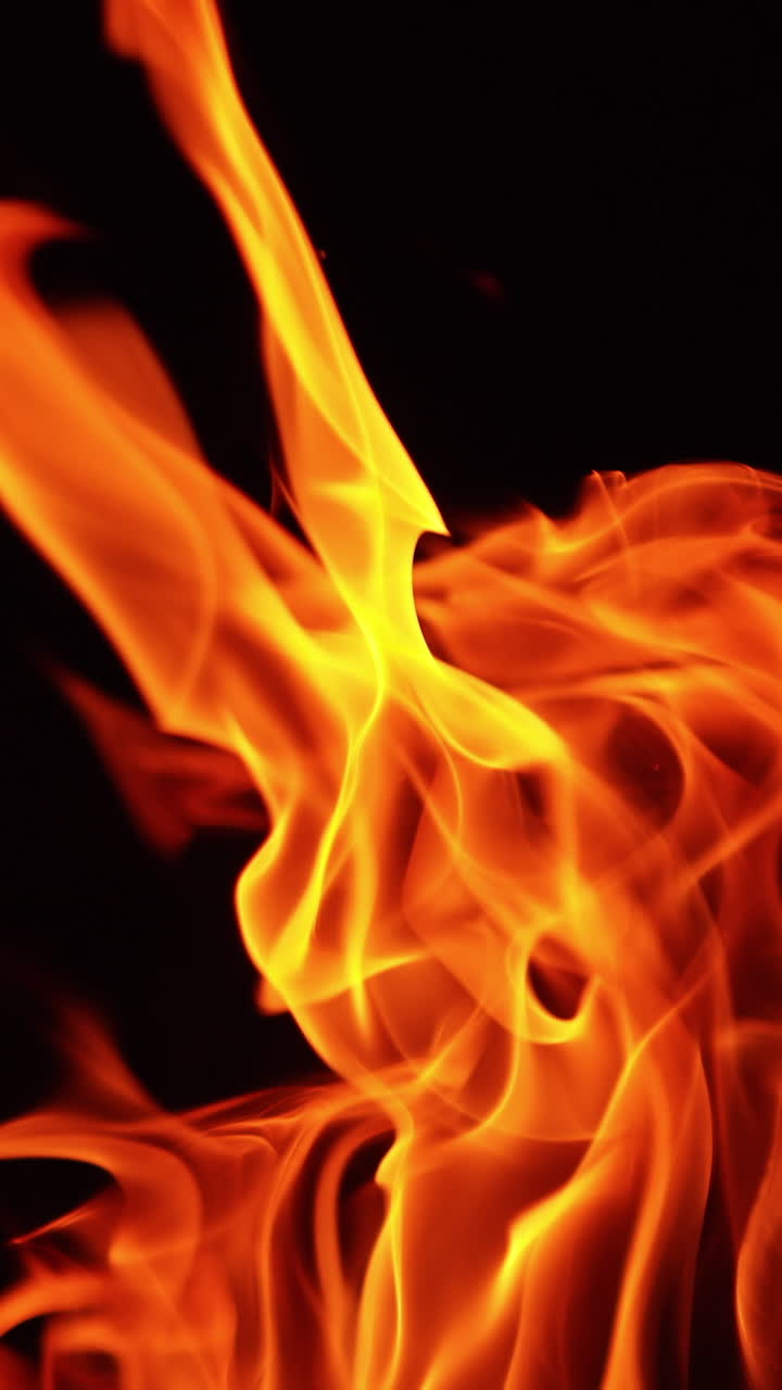 Fiamma vivida che si alza nell'oscurità. Lingue di fuoco che si muovono nel vento di notte. Primo piano. Video verticale