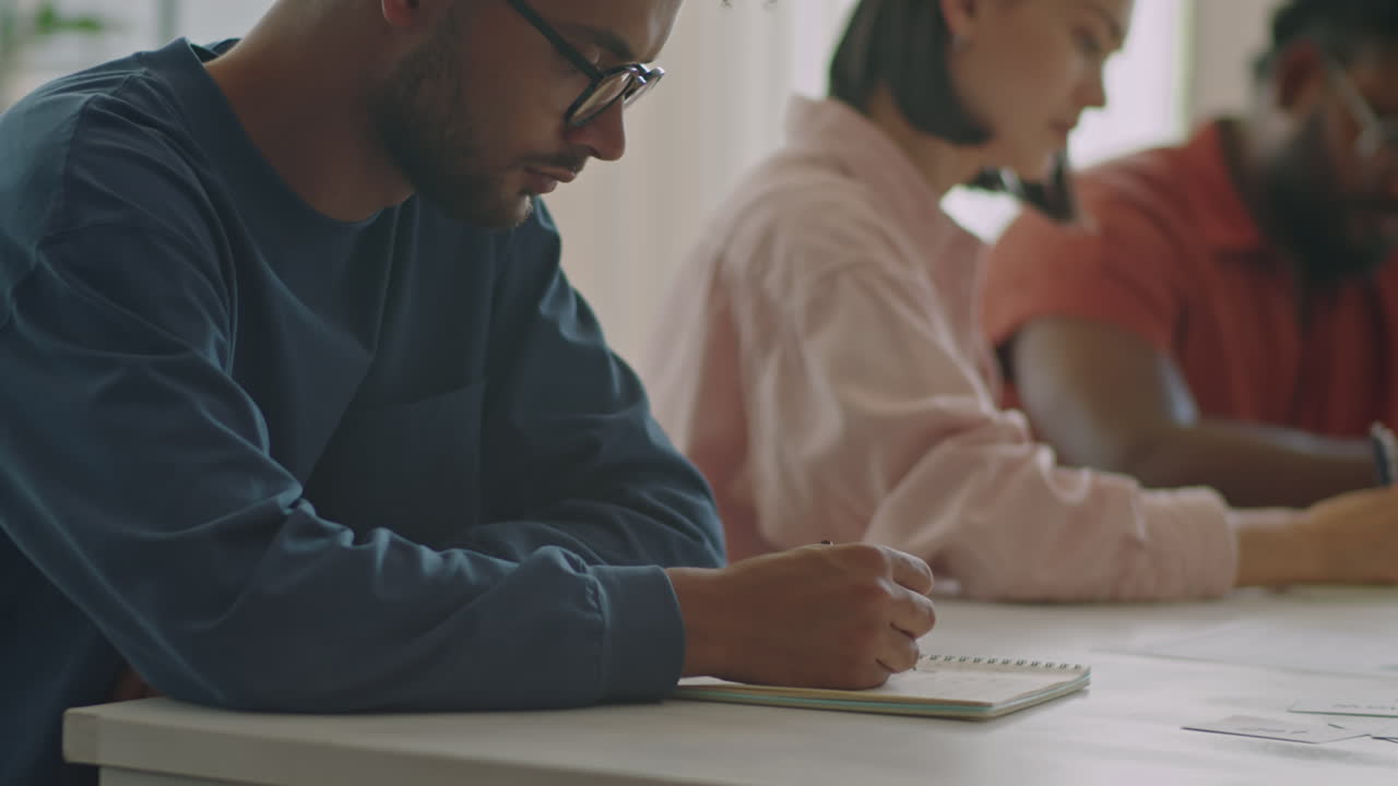Multiracial Migrant Student Writing Test at Desk
