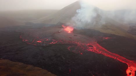 vista aérea del volcán fagradalsfjall en erupción con lava fluyendo a través del suelo del valle meradalir, y saliendo humo, en islandia
