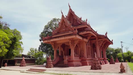 outside view of red buddhist temple surrounded by green trees in koh samui