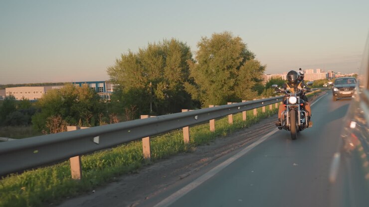 Amici che viaggiano insieme in moto indossando caschi e giubbotti di pelle su una strada aperta al tramonto con un'auto che li segue, che riflette lo spirito di libertà