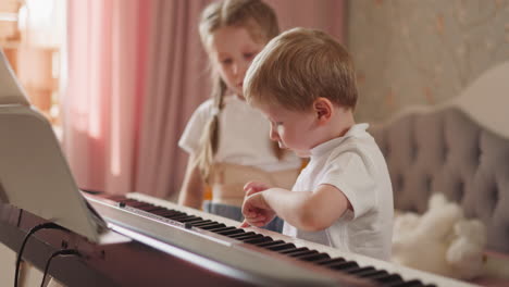 toddler boy asks girl to show right piano keys for theme