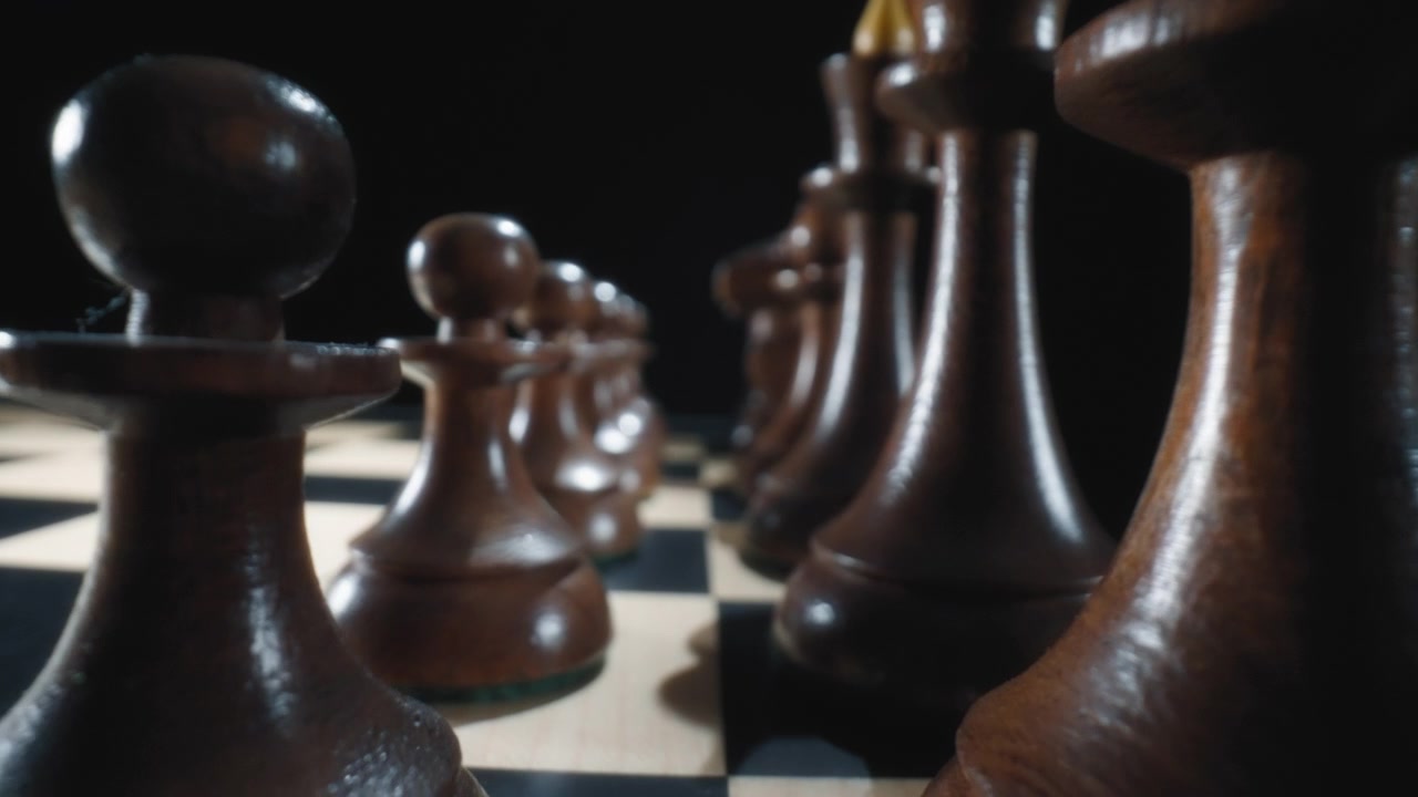 Dolly in macro shot of black wooden chess pieces