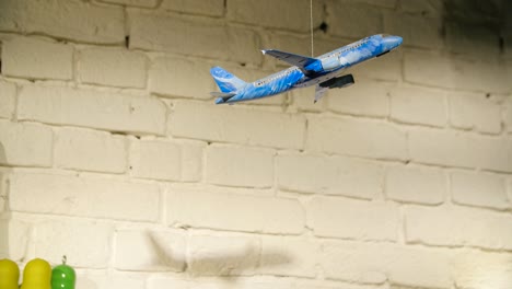 toy airplane hanging from a white brick wall