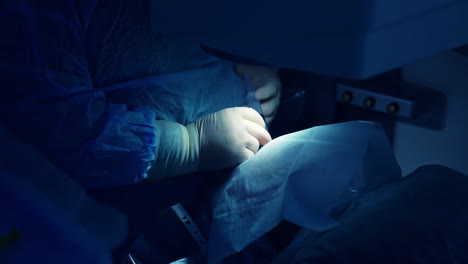 doctor ophthalmologist entering anesthesia. patient is getting eyes anaesthetic during surgery. laser correction. close-up. blue light.